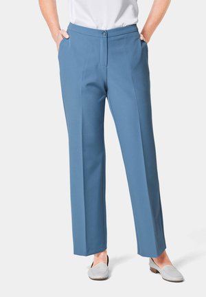 Blauwe op maat gemaakte broek met een knoopsluiting en voorzakken, met een gladde textuur en een recht model. Gecombineerd met grijze instapschoenen.