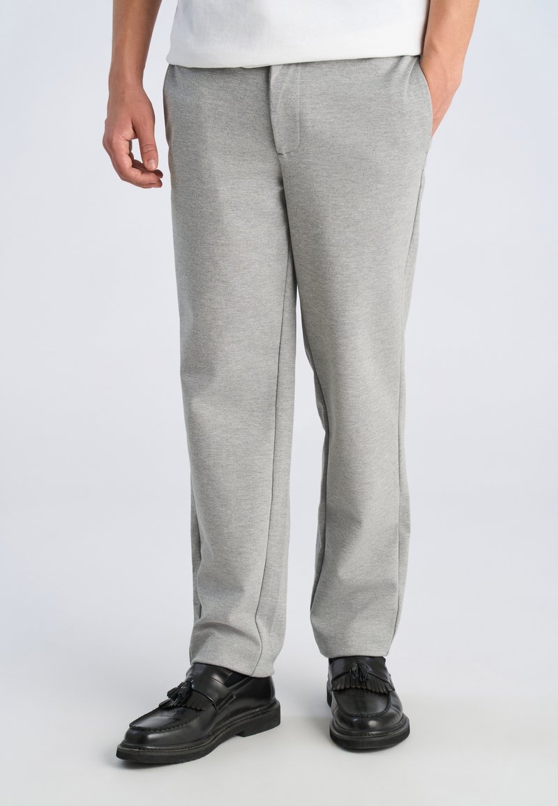 Gray sweatpants in a soft, textured fabric with a relaxed fit, featuring side pockets and a slightly tapered leg design. Paired with black shoes.