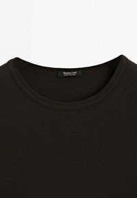 Black ribbed t-shirt with a rounded neckline. Label reads "Massimo Dutti" and indicates it was made in Portugal. Soft texture, fitted design.
