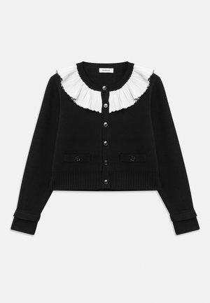 Svart cardigan med en hvit, plisserte volangkrage, seks knappestolinger og ribbestrikkede mansjetter og nederkant. Inkluderer to frontlommer.