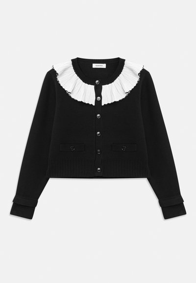 Cardigan nero con colletto a ruffle bianco plissettato, chiusura con sei bottoni e polsini e orlo a coste. Include due tasche frontali.