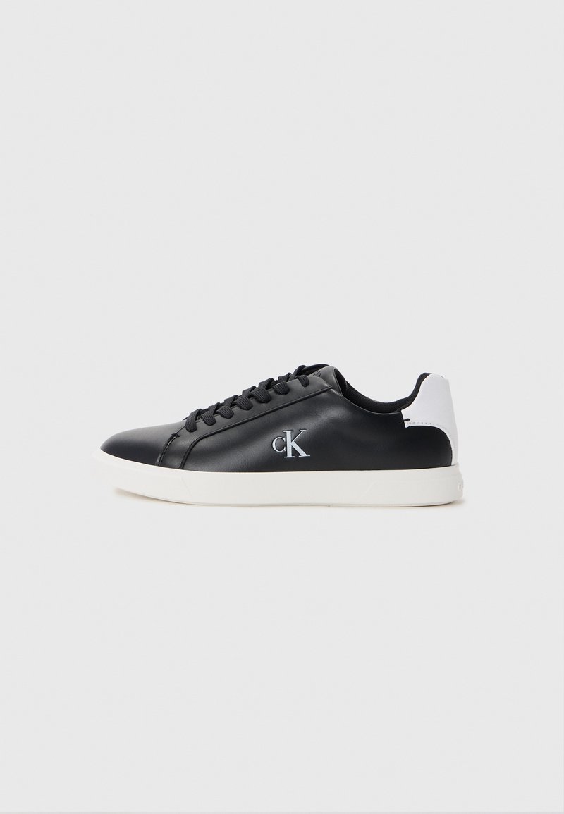 Czarne syntetyczne sneakersy o gładkim wykończeniu, z białym akcentem na pięcie, okrągłym noskiem i czarnymi sznurówkami, z logo "ck" w kolorze srebrnym po boku.