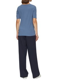 T-shirt bleu à manches courtes avec un col rond, associé à un pantalon large bleu marine. Le tissu semble doux et lisse.