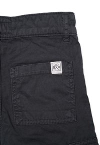 Mörkgrå bomullsshorts med en fyrkantig patch-logotyp på bakfickan, med synliga sömmar och en slät yta.