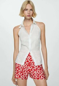 Bílá bezrukávová košile z lněného materiálu s knoflíkovým zapínáním, spárovaná s červenými šortkami s květinovým potiskem. Uvolněný střih a lehká textura.