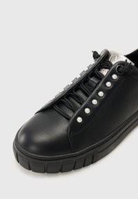 Sneaker in pelle nera con punta rotonda, perle decorative in finta perla e suola in gomma testurizzata con scanalature orizzontali.