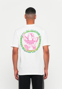 Camiseta de algodão branca com uma grande estampa gr�áfica em rosa e verde nas costas, retratando um personagem com auscultadores e um sinal de paz.