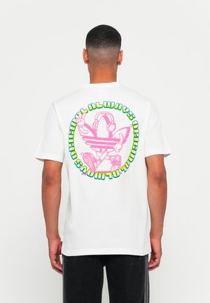Hvid bomulds t-shirt med et stort pink og grønt grafisk print på ryggen, der viser en karakter med hovedtelefoner og et fredstegn.
