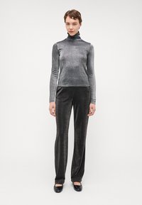 Un haut col roulé gris métallique associé à un pantalon droit noir métallique. Les deux vêtements présentent un léger scintillement et une texture lisse.