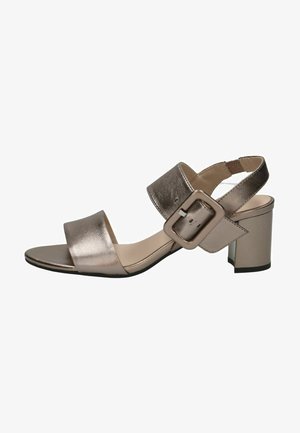 Metallisk sandal med åben tå, blokhæl, bred frontstrop, justerbar ankelrem med spænde og polstret indersål på hvid baggrund.