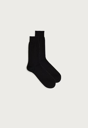 Schwarze Baumwollsocken mit glatter Textur, knöchelhoch und mit geripptem Bündchen. Sie werden paarweise präsentiert und weisen ein einfaches, einfarbiges Design auf.