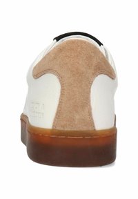 Vit sneaker med en lättbeige mocka hälflik, strukturerad läderöverdel och en brun gummisula. Varumärket är präglat på sidan.