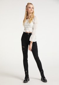 White puff-sleeve top with gathered waist and polka dot texture, paired with black ripped skinny jeans and black lace-up combat boots.