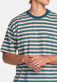 Kortärmad randig t-shirt med horisontella gröna, rosa och blå ränder, med en blå ribbad halsringning och en liten grafisk logotyp.