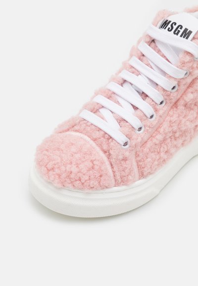 Sapatilha texturizada rosa feita de material fofinho, com atacadores brancos, bico arredondado e sola branca em contraste. Nome da marca na lingueta.