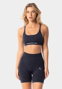  tumši zilā sporta krūšturis un augsto jostasvietu šorti, kas izgatavoti no mīkstas un elastīgas auduma, ar logotipu uz bandas un šortiem.