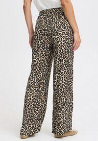 Kalhoty širokého střihu s leopardím potiskem, s elastickým pasem, lehkým materiálem a volným střihem, s béžovým základem a černohnědými skvrnami.