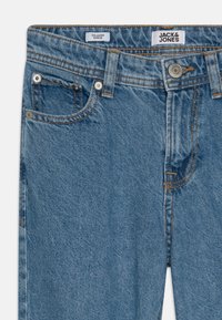 Jeans in denim blu con una vestibilità rilassata, caratterizzati da cuciture arancioni a contrasto, tasche frontali e un'etichetta con logo in vita.