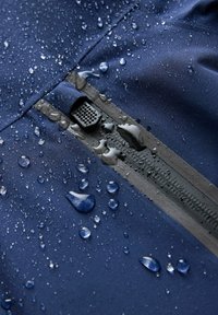 Marineblauwe waterdichte stof met een gestructureerd oppervlak, voorzien van waterdruppels en een zwarte ritssluiting met een mesh-accent.