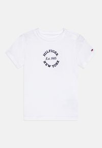 Fehér pamut póló, katonai kékre hímezett "HILFIGER NEW YORK Est. 1985" felirattal, kör alakú mintával. Nyomókával zárható váll.