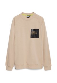 Sudadera beige con cuello redondo. Presenta un bolsillo en el pecho negro con texto y logo. Textura suave y puños acanalados.