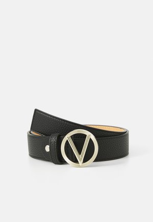Musta nahkavyö, jossa on teksturoitu pinta ja pyöreä kultasävyinen solki, jossa on "V"-muotoilu, kiinnitetty yhdellä nepparilla.