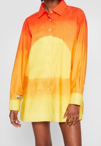 Oversized overhemd met een verloopontwerp van oranje naar geel, gemaakt van katoen, met een label op de linker mouw.