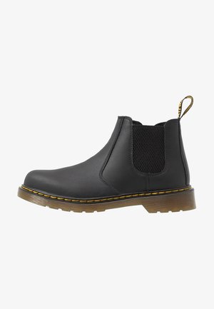 Zwarte Chelsea boot gemaakt van leer met elastiche mesh zijpanelen, gele stiksels en een rubberen zool. Gladde afwerking, met een treklus op de hiel.
