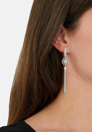 Pendientes de plata con un diseño de flor geométrica y un colgante metálico largo y recto. La textura es suave con un acabado pulido.