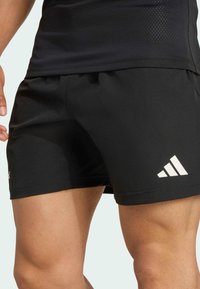 Zwarte sportshorts met een elastische tailleband, gemaakt van gladde stof, met een wit Adidas-logo en een moderne snit voor bewegingsvrijheid.