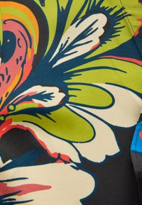 Motif floral abstrait lumineux avec de grandes pétales blanches, des feuilles vertes, et des accents bleus, roses et orange sur fond de tissu.