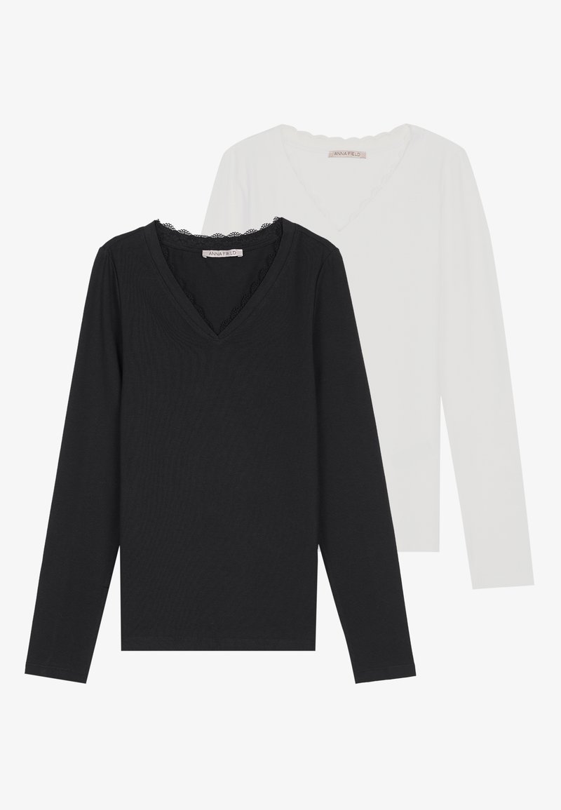 Dve blúzky s dlhým rukávom a V-výstrihom, jedna čierna s vlnkovaným výstrihom, druhá biela, vyrobené z mäkkého, priedušného materiálu.