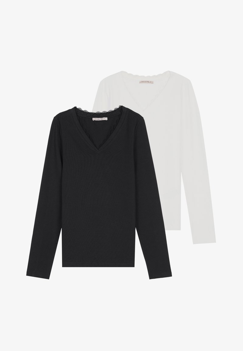 Dve blúzky s dlhým rukávom a V-výstrihom, jedna čierna s vlnkovaným výstrihom, druhá biela, vyrobené z mäkkého, priedušného materiálu.