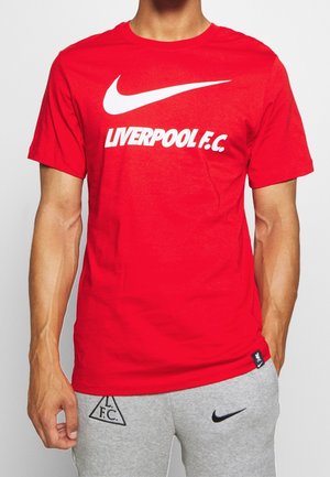 Camiseta de algodón roja con un gran logo blanco de Nike y "LIVERPOOL F.C." en letras blancas en negrita. Cuello redondo y mangas cortas.