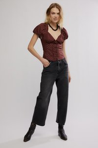 Κόκκινο πουά μπλουζάκι με κοντά φουσκωτά μανίκια, λαιμόκοψη σε σχήμα V και κουμπιά, συνδυασμένο με ψηλόμεσα μαύρα τζιν και μαύρες μποτάκια αστραγάλου.