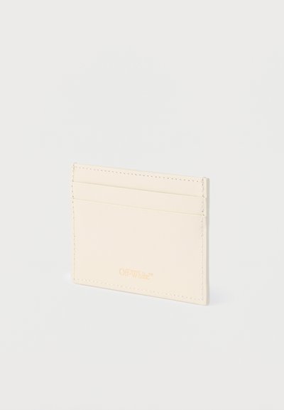 Λεπτό μπεζ δερμάτινο πορτοφόλι για κάρτες με τρεις οριζόντιες θήκες και διακριτικό χρυσό λογότυπο «Off-White» που είναι χαραγμένο στο κάτω κέντρο.