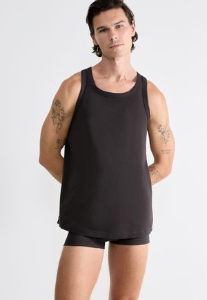 Zwarte mouwloze tanktop van een zacht, glad materiaal met een ronde halslijn en een ontspannen pasvorm, gecombineerd met bijpassende donkere shorts.