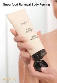 AHAVA Superfood Renewal Body Peeling i en beige tub med svart lock; innehåller text som anger ingredienser: grönkål och gurkmeja.