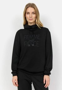 Felpa nera con cappuccio in morbido tessuto, dotata di collo alto e lacci. Presenta la scritta "FEMME and FIERCE" in un design a contrasto.