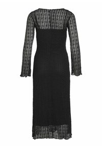 Melna garām piedurknēm kleita ar teksturētu adījumu, pieguļošs augšdaļa un izplūdušs apakšmalu. Iedvesmotā apaļa kakla izgriezums un caurspīdīgas piedurknes.