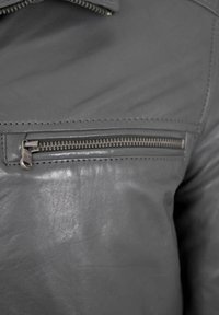 Gray leather jacket featuring a zipped pocket, smooth texture, stitched detailing, and a sleek design without additional embellishments.