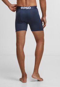 Boxers bleus marins en tissu extensible, avec un logo PSD blanc sur la ceinture et une coupe ajustée avec une longueur mi-cuisse.