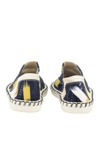 Zapatos slip-on con parte superior de textil impreso en azul marino y amarillo, acentos en beige y costuras texturizadas a lo largo de la suela.