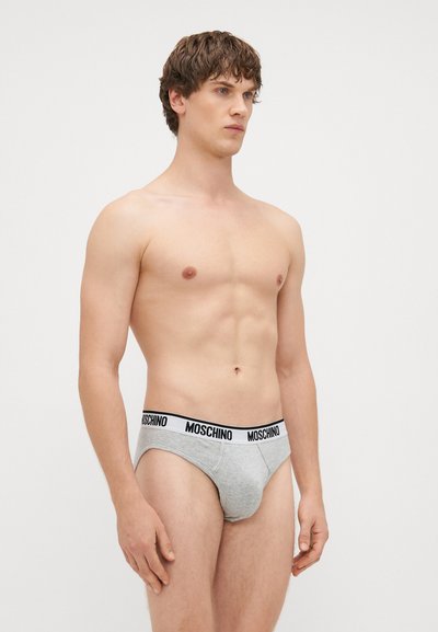 Hallgrayst puuvillast aluspüksid musta Moschino logoga vöökohtades. Pehme tekstuur, keha lähedane lõige ja kesk kõrgus. Täiendavaid detaile ei ole.