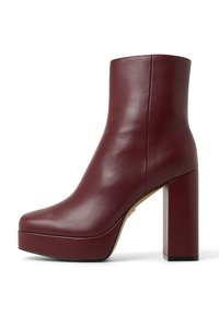 Burgundy leather ankle boots with a smooth texture, square toe, high block heel, and platform sole, featuring minimalistic design.