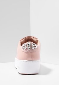Sneaker platform rosa con suola bianca e gemme trasparenti decorativi sulla linguetta del tallone, mostrato di spalle su una superficie bianca.