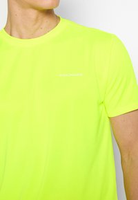Neon gul atletisk t-shirt med rund halsudskæring, korte ærmer og diskret "ENDURANCE" branding i hvid på brystet. Glat tekstur.