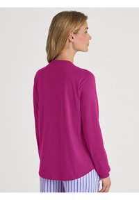 Fuchsia langemouwshirt met een ronde halslijn, zachte textuur en een afgeronde zoom, gecombineerd met gestreepte pyjamabroek in blauw en wit.