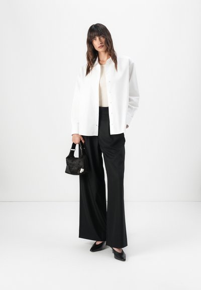 White button-up shirt, cream top underneath, black wide-leg trousers, black pointed heels, and a small black handbag with a fur texture.
