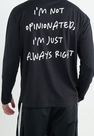 Černé tričko s dlouhým rukávem se výrazným bílým nápisem na zádech: "NEJSEM NÁZOROVÝ, JEN JSEM VŽDY SPRÁVNÝ." Ležérní střih.